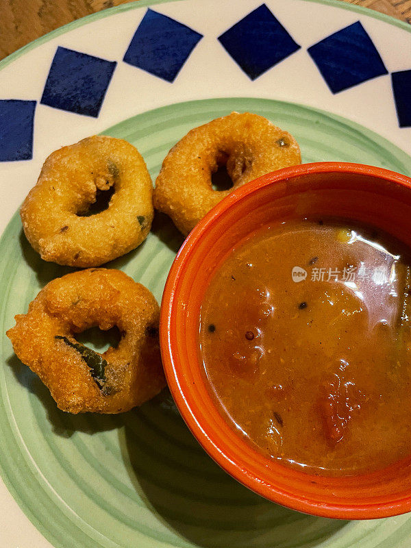 特写图像的图案盘子包含早餐零食自制Medu vada(软油炸)和一碗桑巴(辣扁豆和蔬菜炖)，美味的甜甜圈由Vigna mungo(黑扁豆)，高架视图